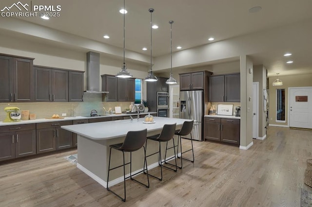 16277 Gammon Ct, Monument, CO 80132 - kitchen with appliances with stainless steel finishes, wall chimney exhaust hood, light countertops, dark brown cabinetry, and decorative backsplash