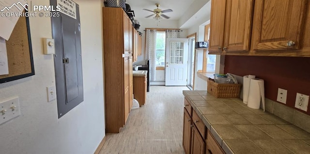 414 7th St, Hugo, CO 80821 - kitchen with tile countertops, brown cabinetry, light wood-style floors, ceiling fan, and electric panel