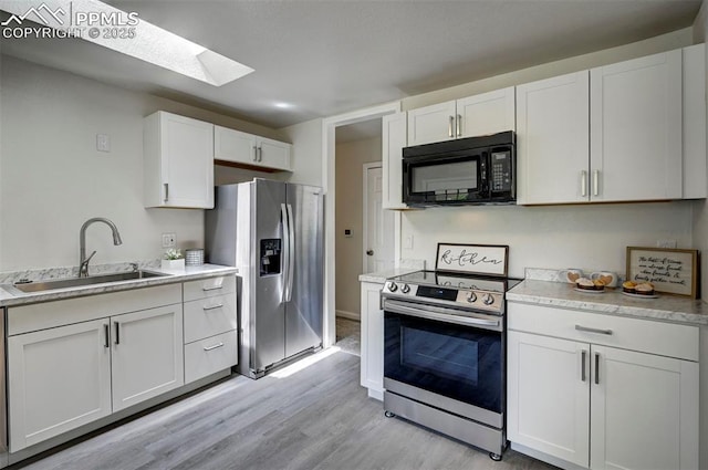 1135 Server Dr, Colorado Springs, CO 80910 - kitchen with stainless steel appliances, a sink, a skylight, light wood finished floors, and white cabinetry