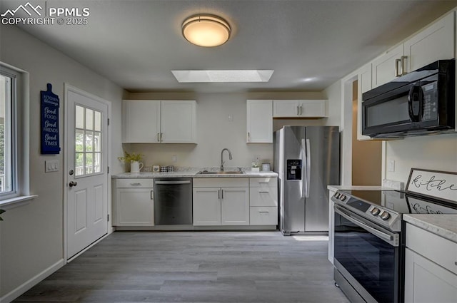 1135 Server Dr, Colorado Springs, CO 80910 - kitchen featuring stainless steel appliances, a skylight, a sink, and light wood-style flooring