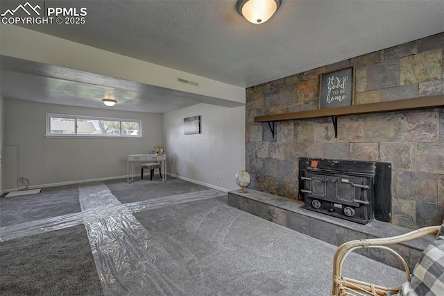 1135 Server Dr, Colorado Springs, CO 80910 - unfurnished living room with a wood stove, carpet floors, a textured ceiling, and baseboards