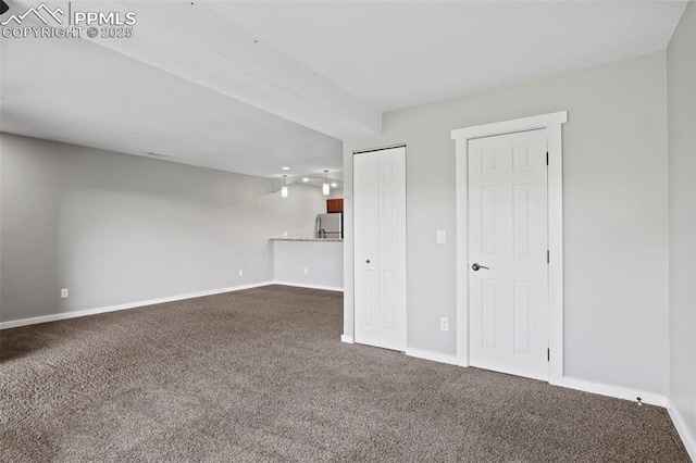 128 W Rockrimmon Blvd Unit 105, Colorado Springs, CO 80919 - unfurnished living room with dark colored carpet and baseboards