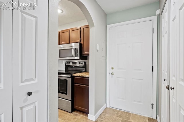 128 W Rockrimmon Blvd Unit 105, Colorado Springs, CO 80919 - kitchen with appliances with stainless steel finishes, arched walkways, light countertops, and light stone finish flooring