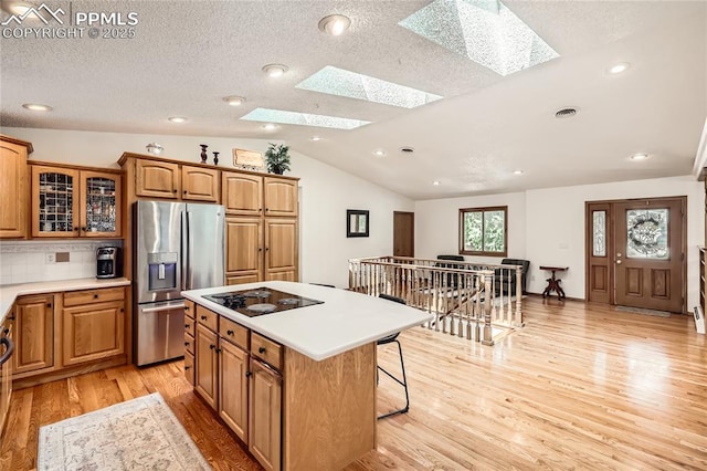 3660 E Wade Ln, Colorado Springs, CO 80917 - kitchen featuring stainless steel refrigerator with ice dispenser, a skylight, a kitchen island, black electric stovetop, and light wood-style floors