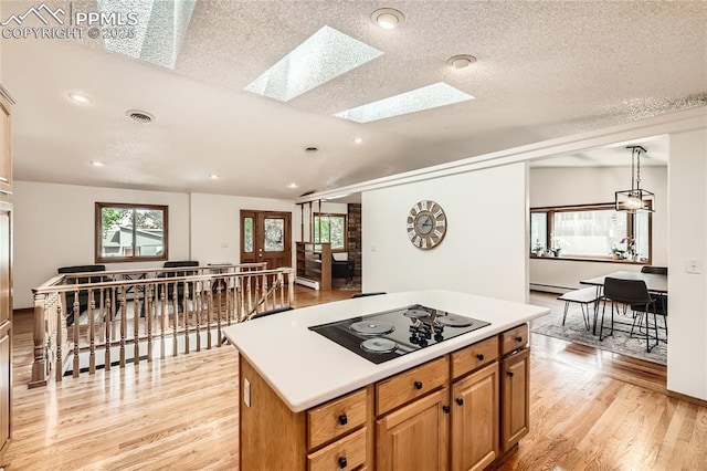 3660 E Wade Ln, Colorado Springs, CO 80917 - kitchen with black electric stovetop, light wood-style flooring, light countertops, a skylight, and recessed lighting