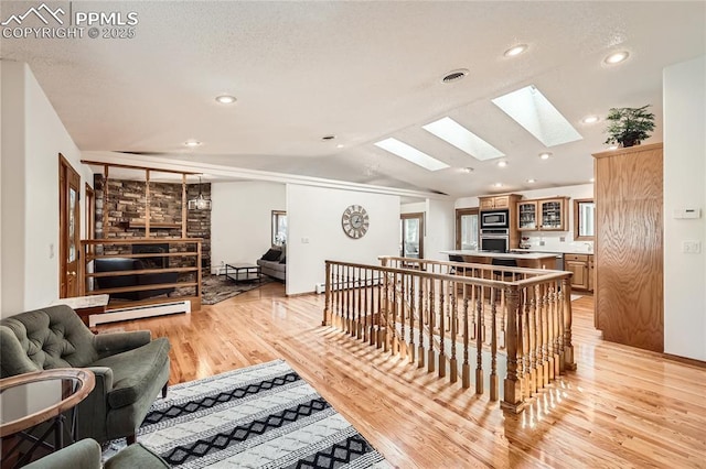 3660 E Wade Ln, Colorado Springs, CO 80917 - living area with a skylight, light wood-style floors, lofted ceiling, baseboard heating, and recessed lighting