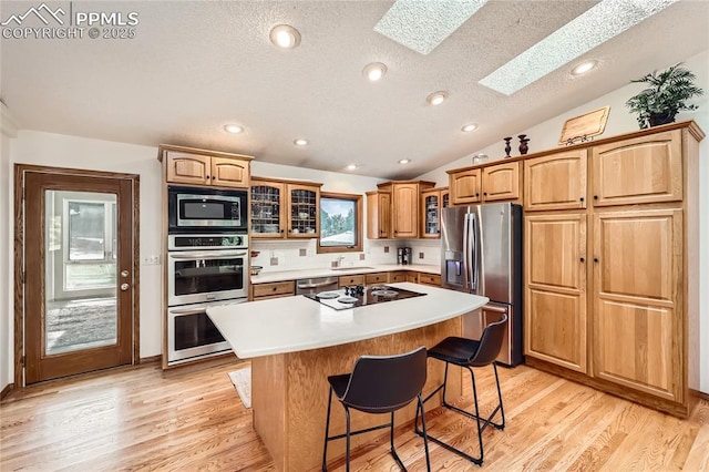 3660 E Wade Ln, Colorado Springs, CO 80917 - kitchen with stainless steel appliances, a skylight, glass insert cabinets, a center island, and a textured ceiling