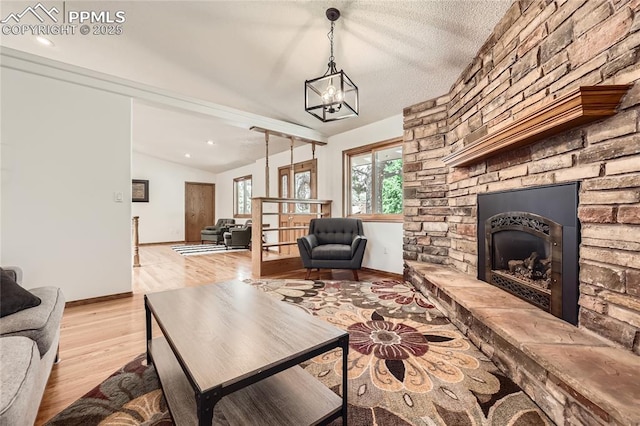 3660 E Wade Ln, Colorado Springs, CO 80917 - living area with vaulted ceiling, light wood-style floors, a stone fireplace, baseboards, and a chandelier