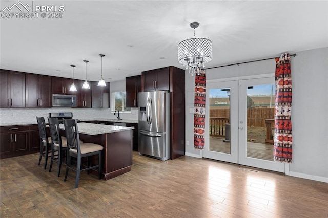 4623 Ranch Cir, Colorado Springs, CO 80918 - kitchen with stainless steel appliances, dark brown cabinets, dark wood finished floors, and a chandelier