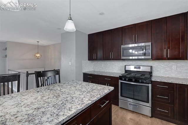 4623 Ranch Cir, Colorado Springs, CO 80918 - kitchen featuring appliances with stainless steel finishes, decorative backsplash, wood finished floors, light stone countertops, and decorative light fixtures