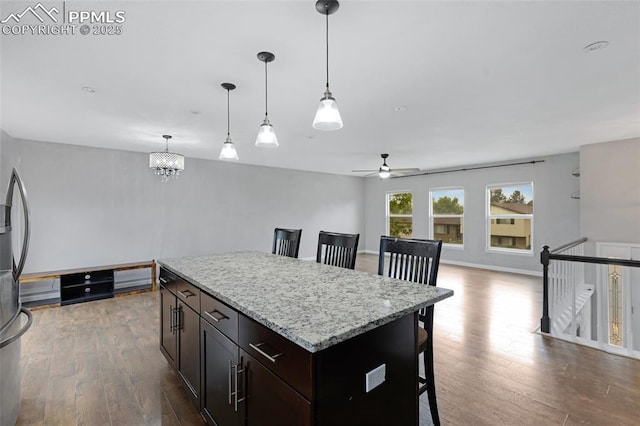 4623 Ranch Cir, Colorado Springs, CO 80918 - kitchen featuring a ceiling fan, a kitchen bar, dark wood finished floors, decorative light fixtures, and a chandelier