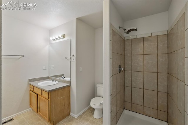 688 Bosque Vista Pt, Colorado Springs, CO 80916 - bathroom featuring vanity, toilet, a tile shower, baseboards, and tile patterned floors