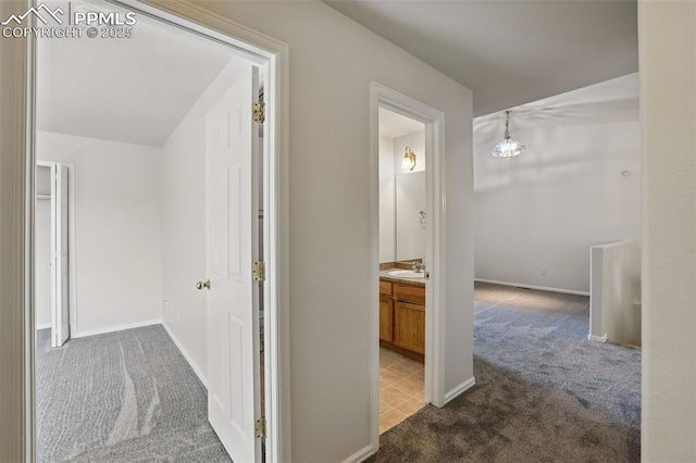688 Bosque Vista Pt, Colorado Springs, CO 80916 - hallway featuring carpet, a sink, baseboards, and a chandelier