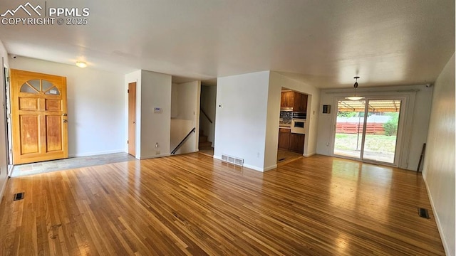 2204 Glenn Summer Rd, Colorado Springs, CO 80909 - unfurnished living room featuring hardwood / wood-style flooring and stairway