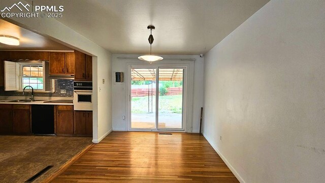 2204 Glenn Summer Rd, Colorado Springs, CO 80909 - kitchen with white oven, wood finished floors, light countertops, and plenty of natural light