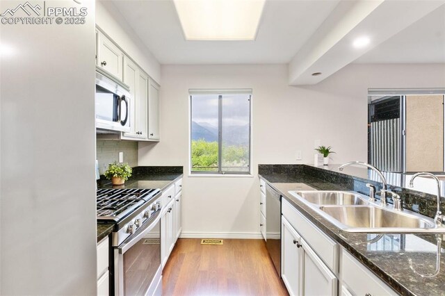 942 Fontmore Rd Unit B, Colorado Springs, CO 80904 - kitchen with appliances with stainless steel finishes, a sink, white cabinetry, light wood-style floors, and baseboards