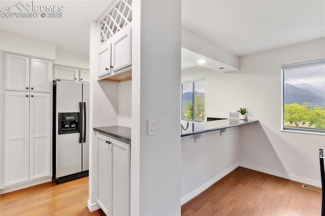 942 Fontmore Rd Unit B, Colorado Springs, CO 80904 - kitchen featuring stainless steel refrigerator with ice dispenser, light wood finished floors, dark countertops, baseboards, and white cabinets