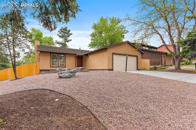 4408 Winding Cir, Colorado Springs, CO 80917 - view of front of home featuring stucco siding, an attached garage, a chimney, and driveway