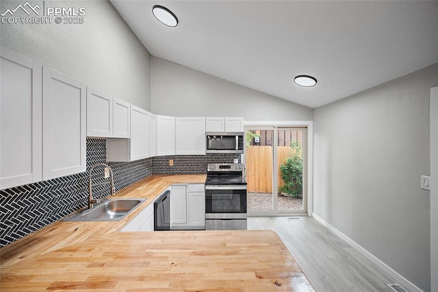4408 Winding Cir, Colorado Springs, CO 80917 - kitchen with appliances with stainless steel finishes, wooden counters, decorative backsplash, wood finished floors, and white cabinets