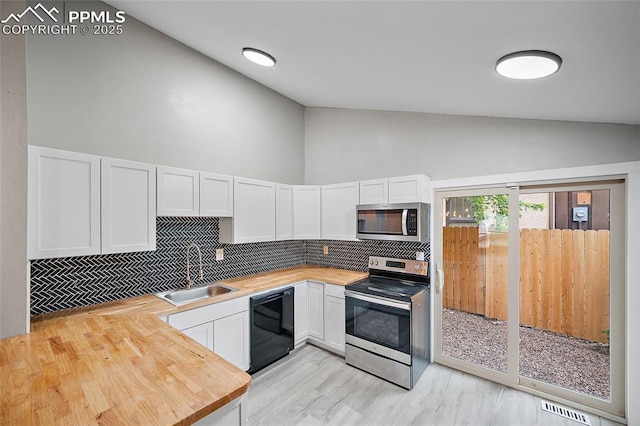 4408 Winding Cir, Colorado Springs, CO 80917 - kitchen with stainless steel appliances, wood counters, decorative backsplash, white cabinetry, and high vaulted ceiling