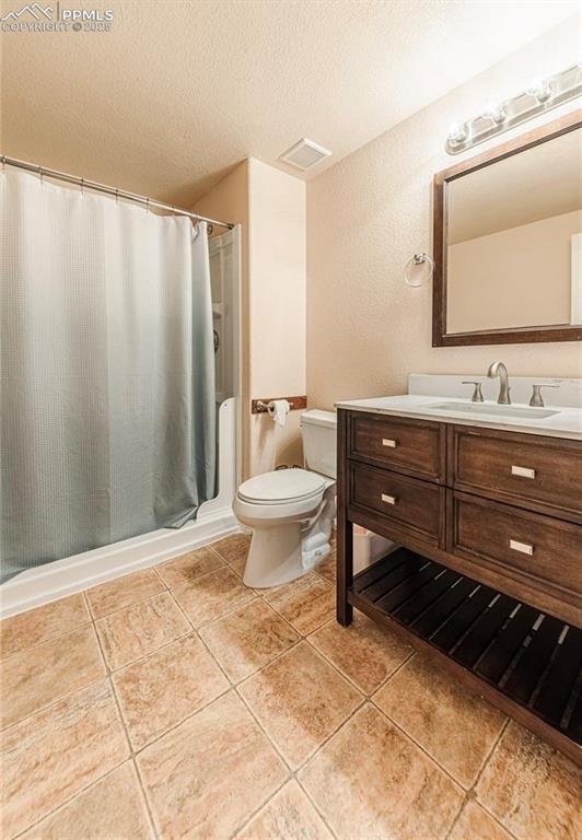 830 Winebrook Way, Fountain, CO 80817 - full bath featuring toilet, vanity, a stall shower, a textured ceiling, and tile patterned floors