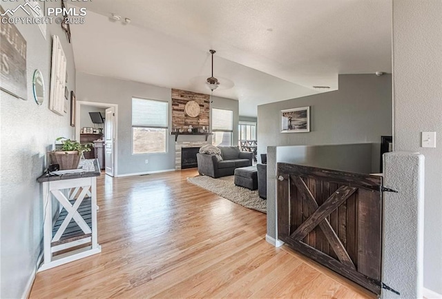 830 Winebrook Way, Fountain, CO 80817 - living area featuring light wood finished floors, a fireplace, baseboards, and vaulted ceiling