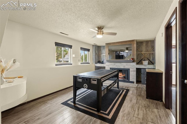 4303 W Eastcrest Cir, Colorado Springs, CO 80916 - game room with a ceiling fan, a fireplace, wood finished floors, baseboards, and a textured ceiling