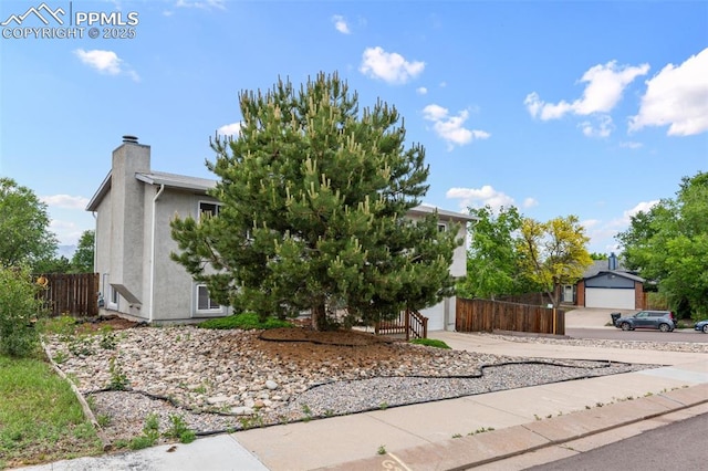 4303 W Eastcrest Cir, Colorado Springs, CO 80916 - view of property hidden behind natural elements featuring driveway, stucco siding, a chimney, and a garage