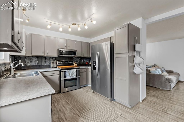 4303 W Eastcrest Cir, Colorado Springs, CO 80916 - kitchen featuring stainless steel appliances, a sink, gray cabinetry, decorative backsplash, and light wood-type flooring