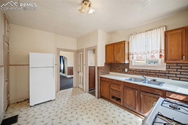 117 S Limit St, Colorado Springs, CO 80905 - kitchen with freestanding refrigerator, a sink, light floors, brown cabinets, and range