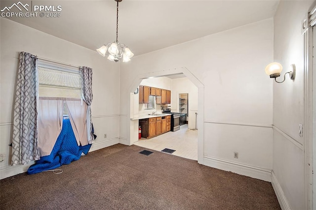 117 S Limit St, Colorado Springs, CO 80905 - unfurnished dining area featuring light carpet, a chandelier, baseboards, arched walkways, and a sink