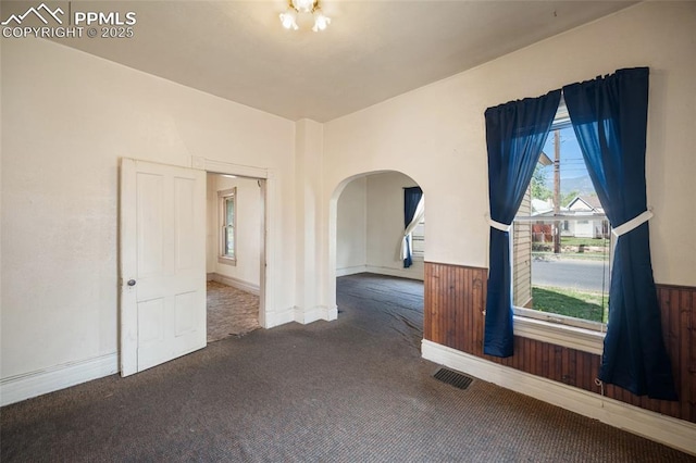 117 S Limit St, Colorado Springs, CO 80905 - carpeted empty room with arched walkways, wainscoting, and wooden walls