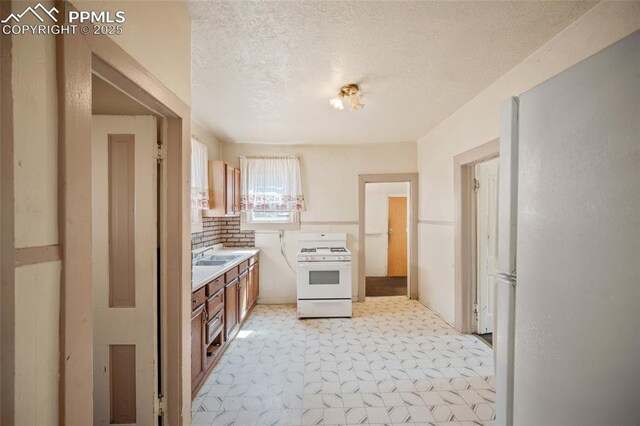 117 S Limit St, Colorado Springs, CO 80905 - kitchen with white appliances, a textured ceiling, light countertops, a sink, and brown cabinetry
