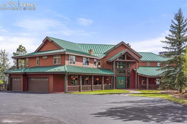 215 Morning Sun Dr, Woodland Park, CO 80863 - view of front of house featuring a standing seam roof, metal roof, a chimney, an attached garage, and asphalt driveway