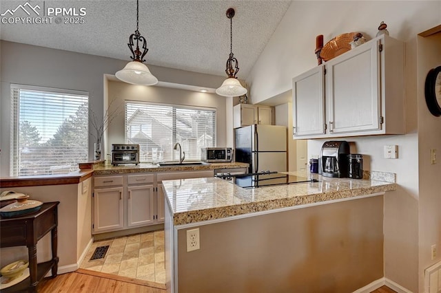 4120 Autumn Heights Dr Unit B, Colorado Springs, CO 80906 - kitchen with freestanding refrigerator, a peninsula, a textured ceiling, healthy amount of natural light, and tile counters