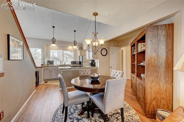 4120 Autumn Heights Dr Unit B, Colorado Springs, CO 80906 - dining area featuring light wood-type flooring, a textured ceiling, lofted ceiling, and a chandelier