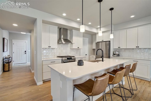 6471 Rolling Creek Dr, Colorado Springs, CO 80924 - kitchen with wall chimney exhaust hood, stainless steel appliances, light wood-type flooring, a sink, and decorative backsplash
