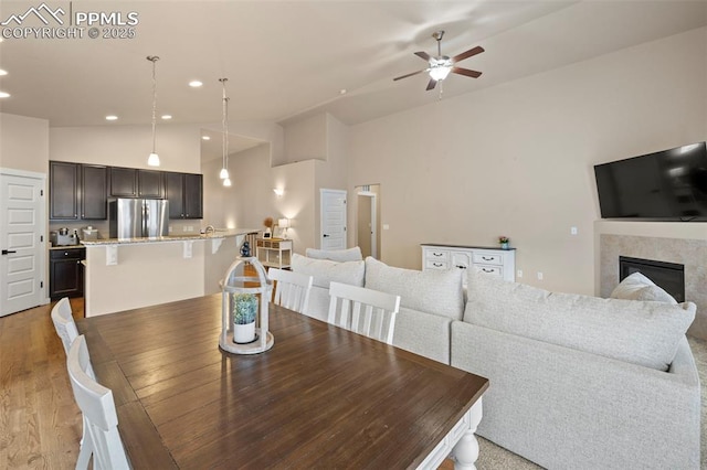 6374 Tramore Way, Colorado Springs, CO 80923 - dining room with lofted ceiling, ceiling fan, light wood-style floors, recessed lighting, and a glass covered fireplace