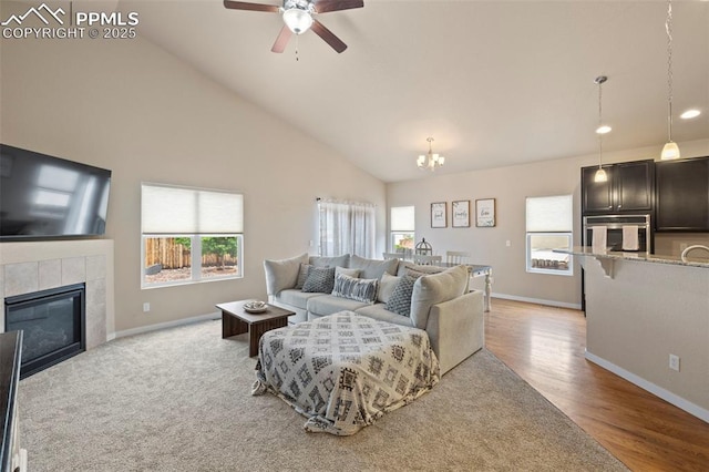 6374 Tramore Way, Colorado Springs, CO 80923 - living room with a chandelier, a ceiling fan, a fireplace, high vaulted ceiling, and light wood finished floors