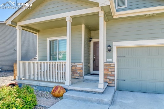 6676 Liberator Trl, Colorado Springs, CO 80925 - property entrance featuring covered porch, a garage, and stone siding