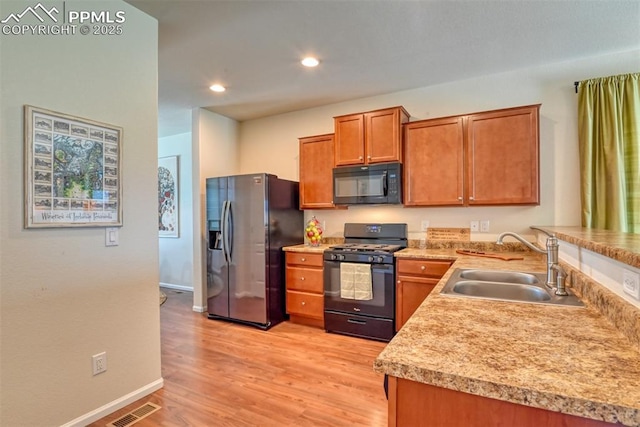 6676 Liberator Trl, Colorado Springs, CO 80925 - kitchen with black appliances, a sink, baseboards, light wood-style flooring, and brown cabinetry