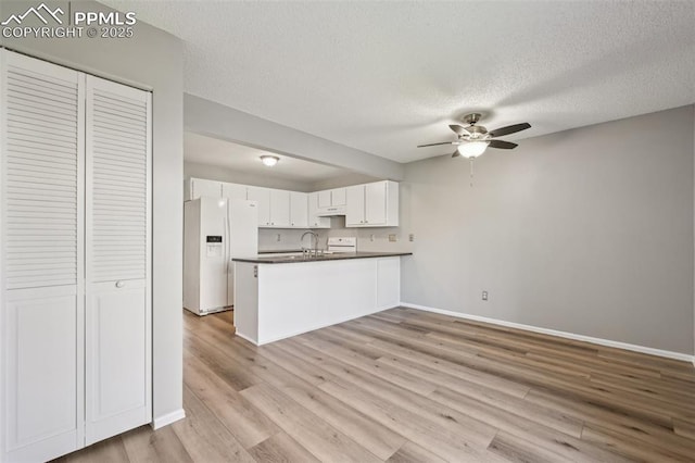 2013 Erin Loop, Colorado Springs, CO 80918 - kitchen with white fridge with ice dispenser, a peninsula, dark countertops, ceiling fan, and baseboards