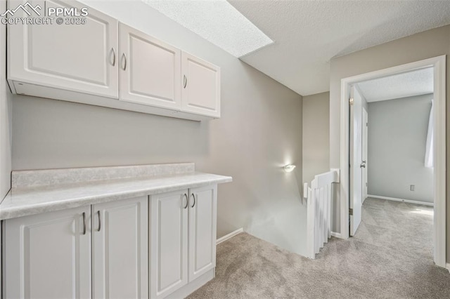 2013 Erin Loop, Colorado Springs, CO 80918 - hall featuring light colored carpet, baseboards, a textured ceiling, and an upstairs landing
