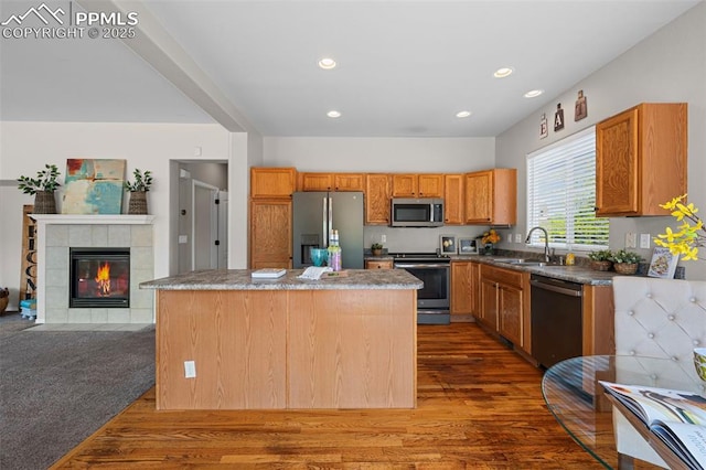 8370 Lupan Dr, Colorado Springs, CO 80951 - kitchen featuring appliances with stainless steel finishes, dark wood finished floors, a kitchen island, recessed lighting, and a fireplace