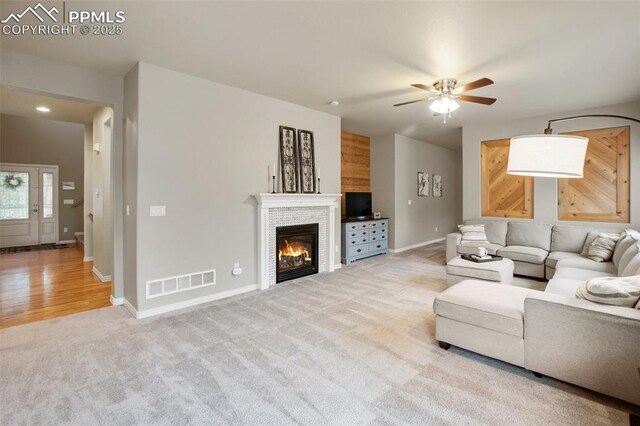 6874 Quiet Pond Pl, Colorado Springs, CO 80923 - living room with ceiling fan, light carpet, a glass covered fireplace, and baseboards