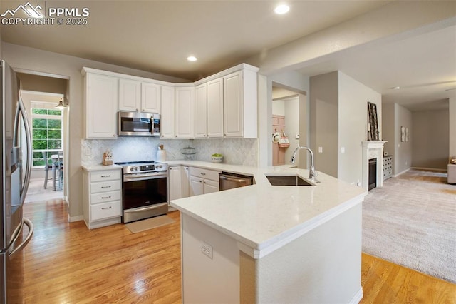 6874 Quiet Pond Pl, Colorado Springs, CO 80923 - kitchen featuring appliances with stainless steel finishes, a sink, a peninsula, white cabinets, and light wood finished floors
