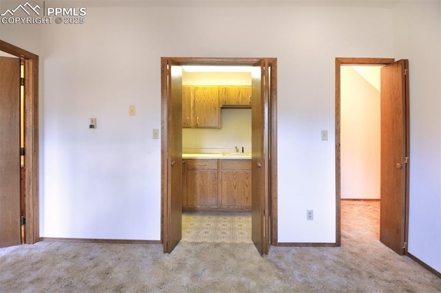 7770 N Topeka Ave, Cascade, CO 80809 - kitchen with light carpet, brown cabinetry, a sink, baseboards, and light countertops