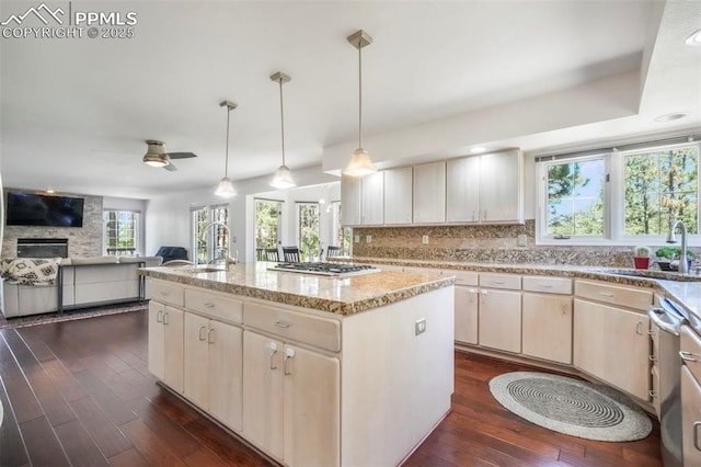 1240 Lone Scout Lookout, Monument, CO 80132 - kitchen with stainless steel appliances, dark wood-type flooring, decorative backsplash, a center island with sink, and light stone countertops