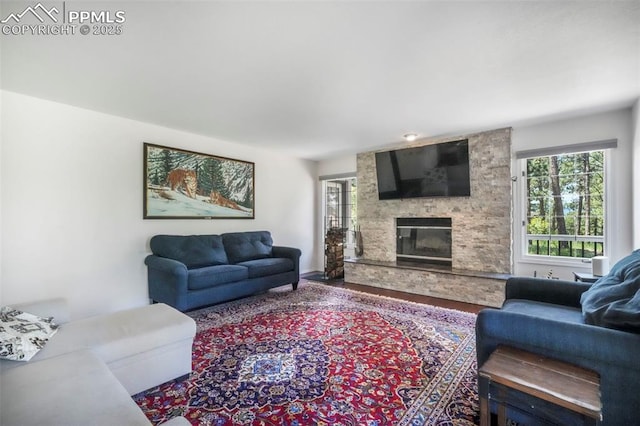 1240 Lone Scout Lookout, Monument, CO 80132 - living room featuring healthy amount of natural light, a stone fireplace, and wood finished floors