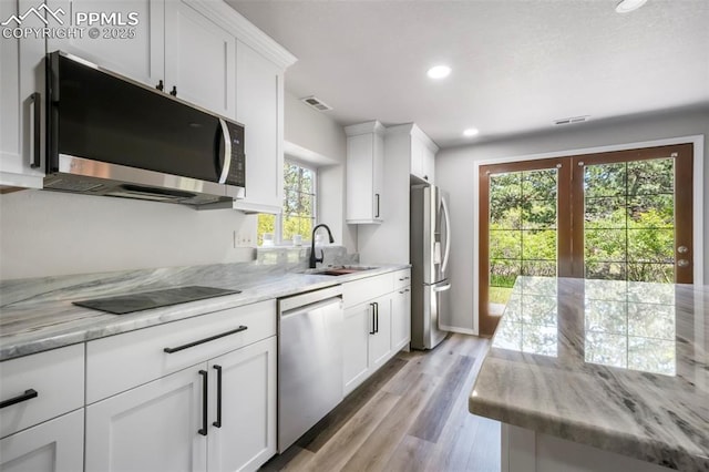 1240 Lone Scout Lookout, Monument, CO 80132 - kitchen featuring stainless steel appliances, white cabinets, recessed lighting, light wood-type flooring, and light stone countertops